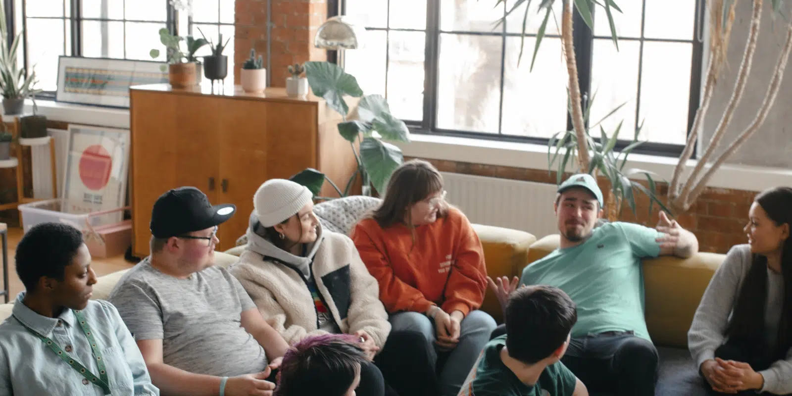Group of young people sat on sofas, listening to Aaron speak