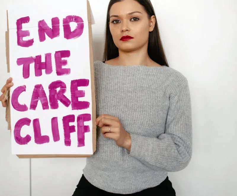 Jasmine sat down holding end the care cliff sign