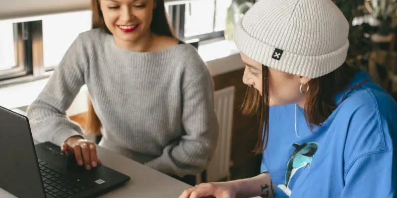 Two students working at laptop