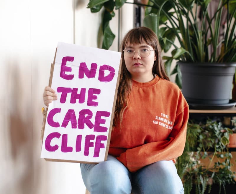 Zara holding end the care cliff sign sat down
