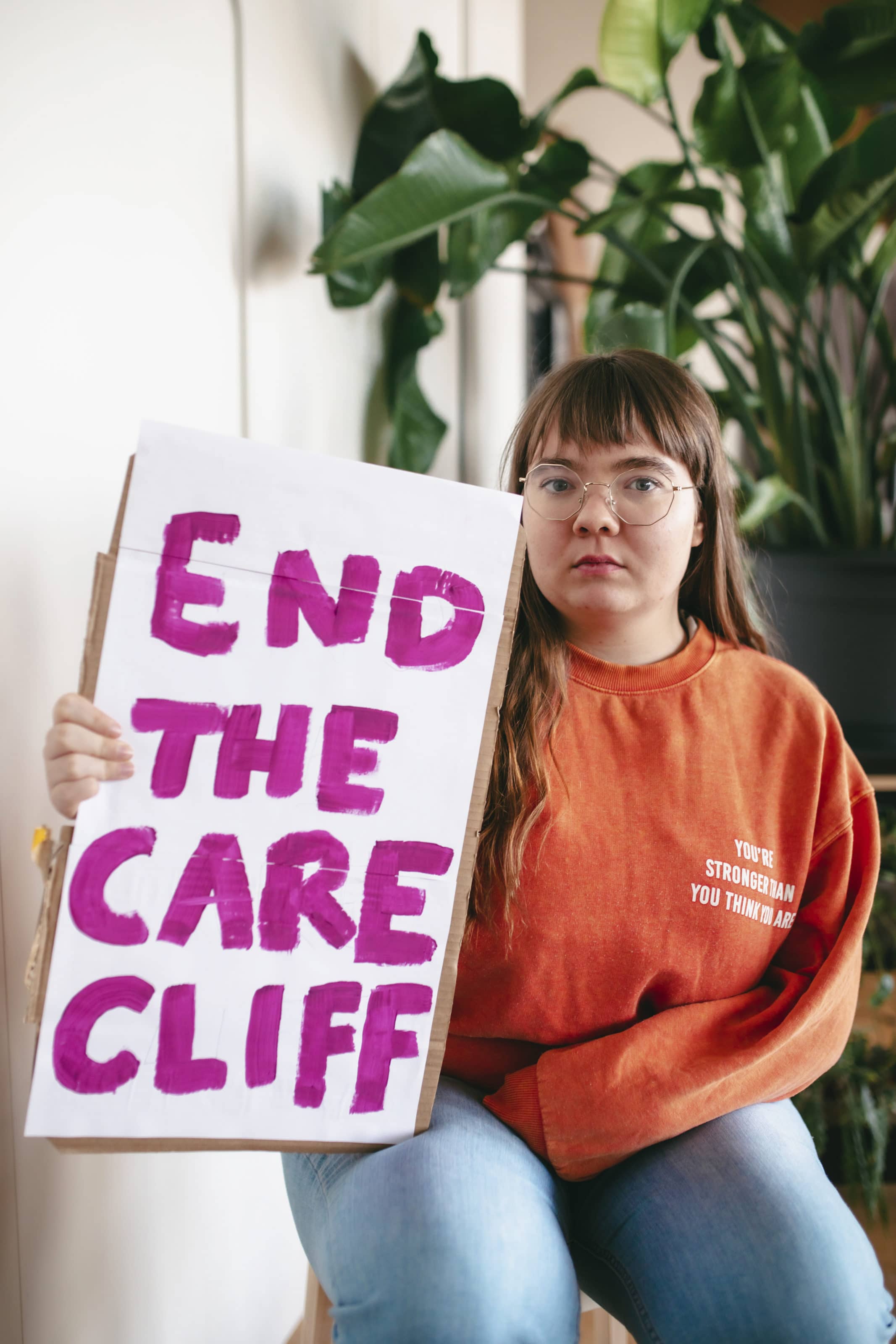 Zara holding end the care cliff sign sat down close up