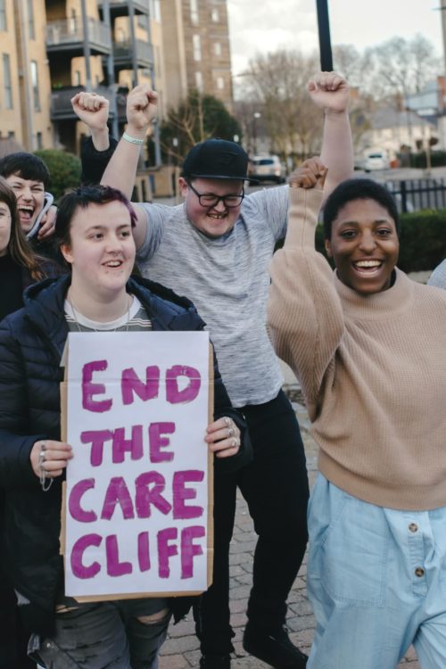 Group of young people with raised fists and end the care cliff sign