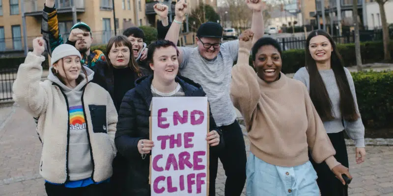Group of young people with raised fists and end the care cliff sign