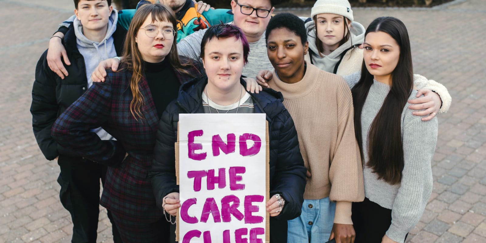 Group of young people staring into camera with end the care cliff sign