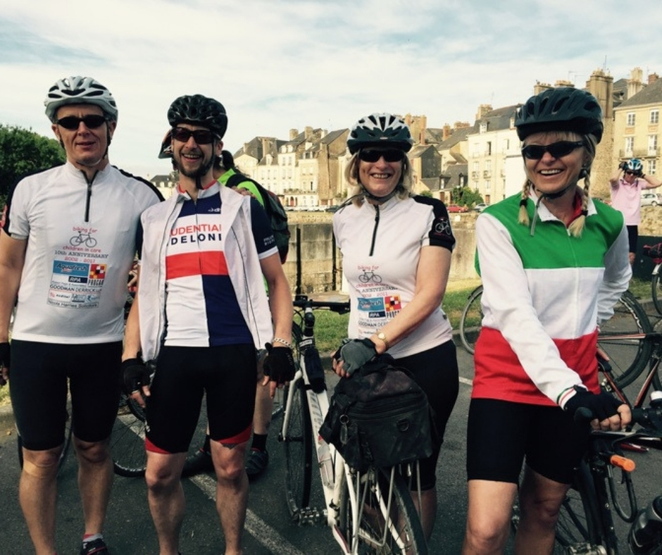 Four riders hold their bikes in a French town