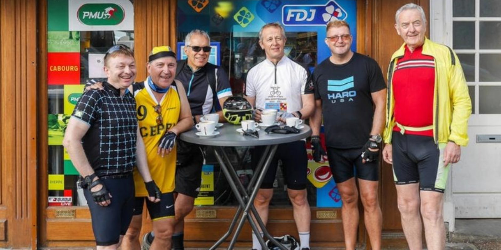 Six riders standing in front of a bar having after finishing their cycle