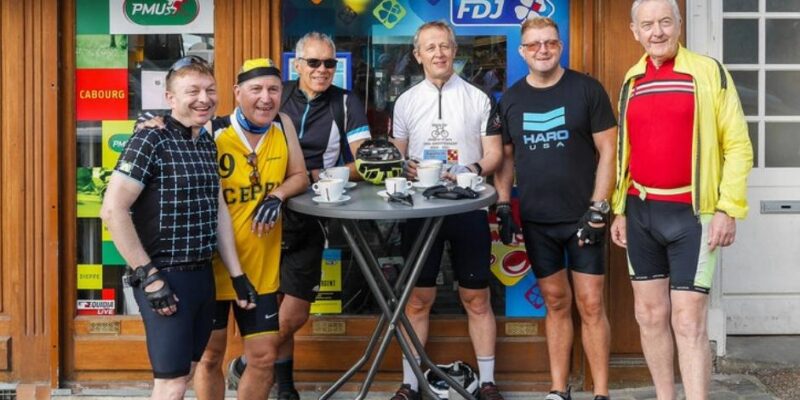 Six riders standing in front of a bar having after finishing their cycle