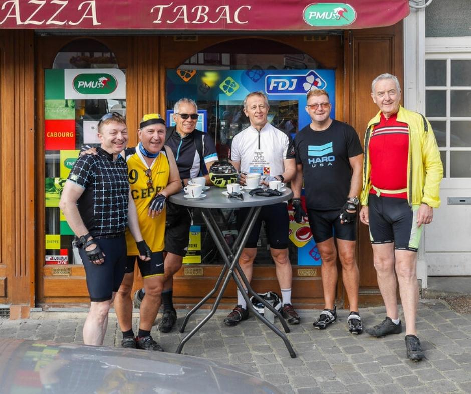 Six riders standing in front of a bar having after finishing their cycle