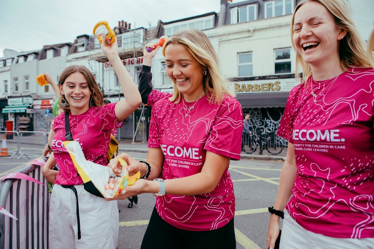 Three women in pink Become tops. One of them is holding an open packet of sweets