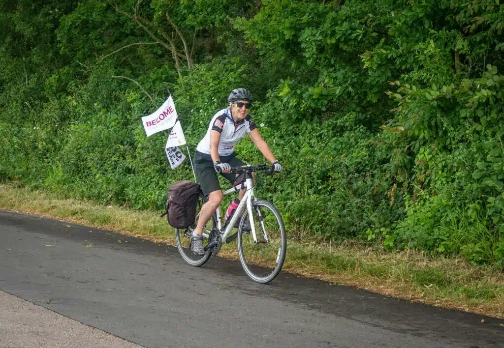 Gill cycling with Become flag on the back of the bike