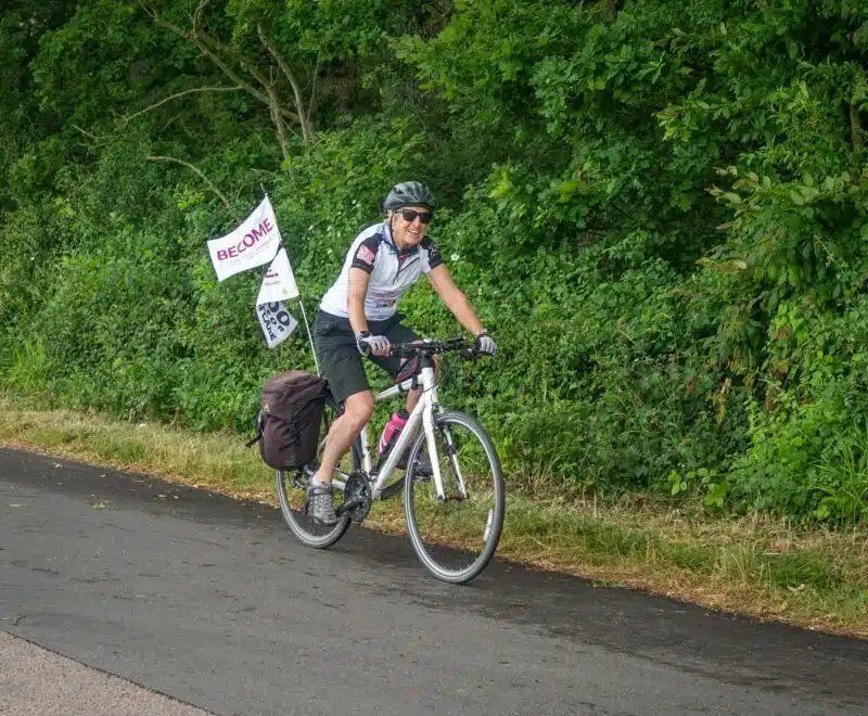 Gill cycling with Become flag on the back of the bike