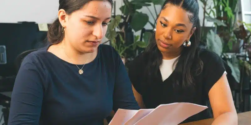 Two people at a desk looking at paper