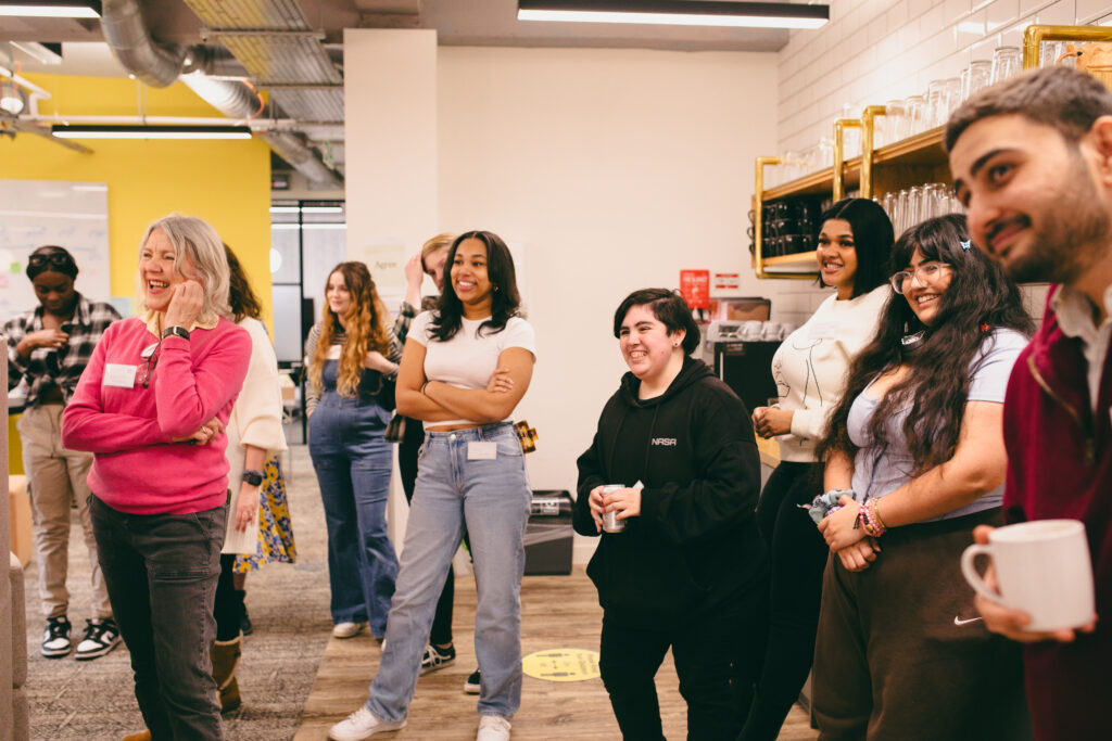 Group of staff and young people smiling watching someone speak