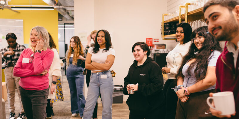 Group of staff and young people smiling watching someone speak